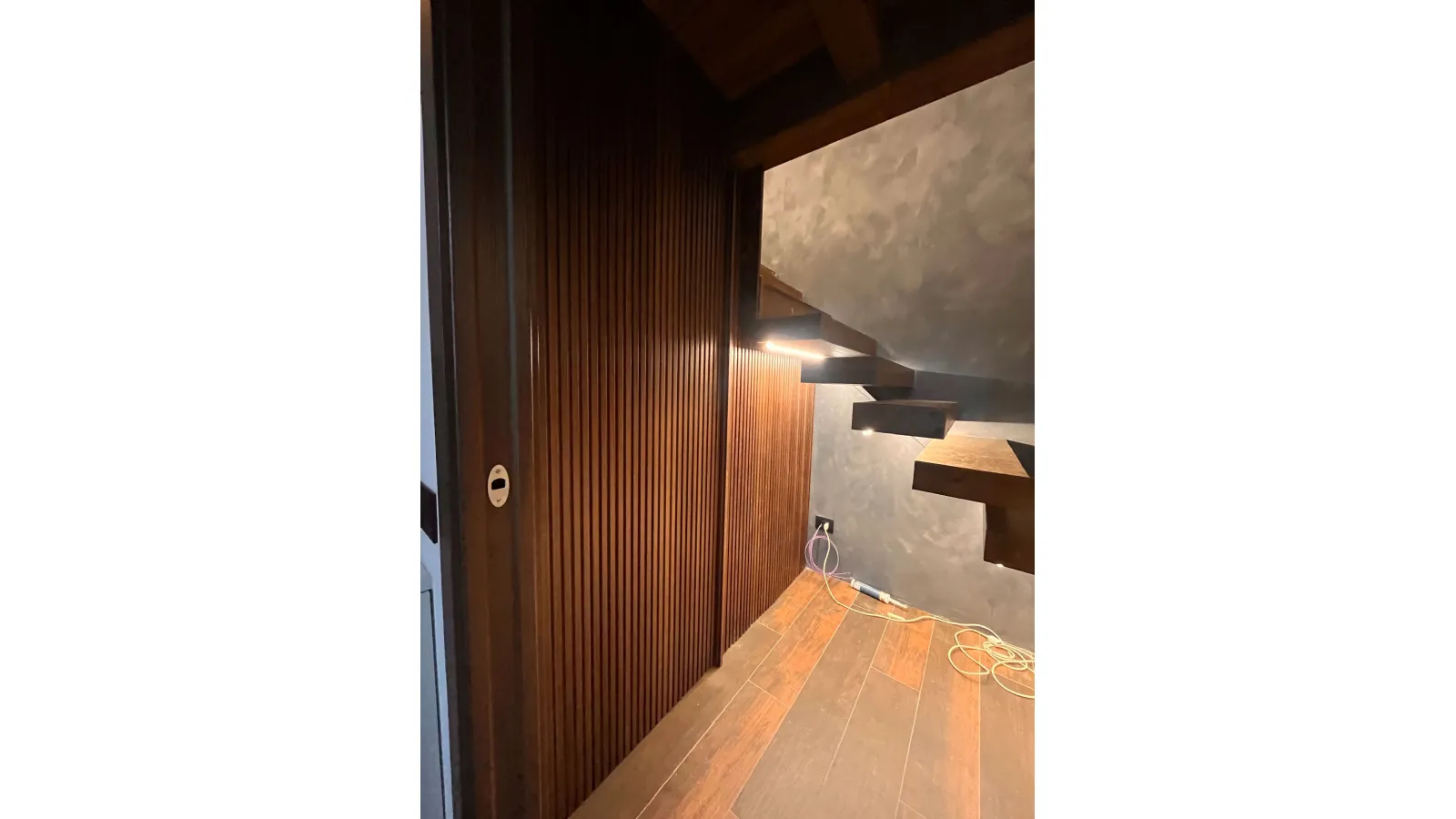 Porta a scomparsa con boiserie in legno a listelli verticali