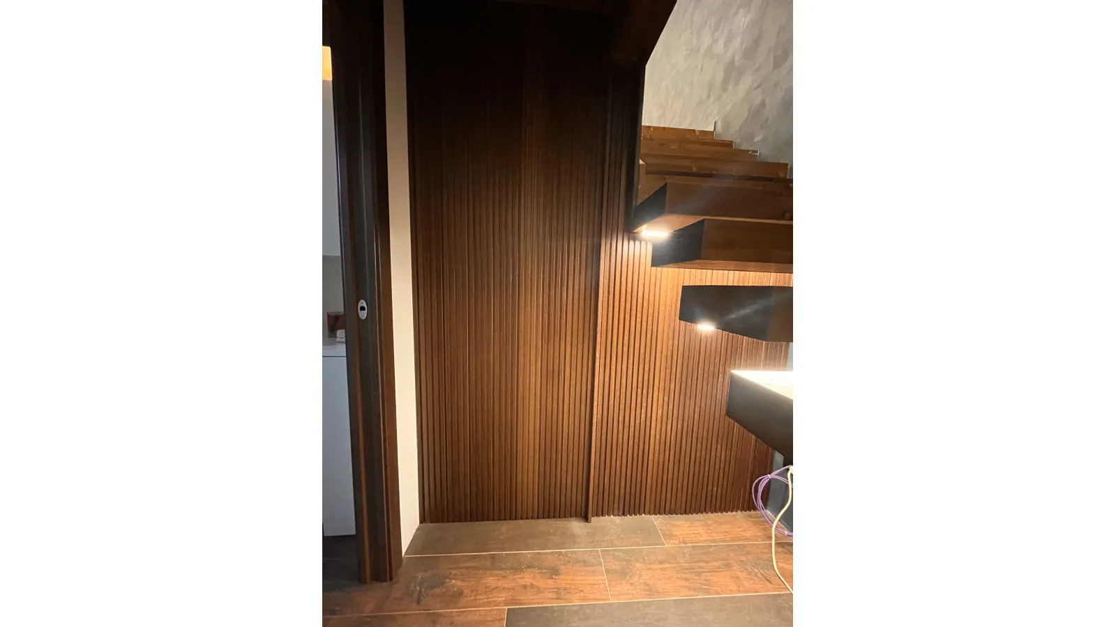 Porta a scomparsa con boiserie in legno a listelli verticali